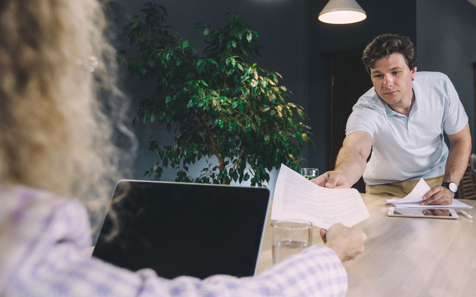 One colleague hands a document across the desk to another. When an agent can't finish, the job and its reason should reach the next worker the same way. Photo: SHVETS production / Pexels.