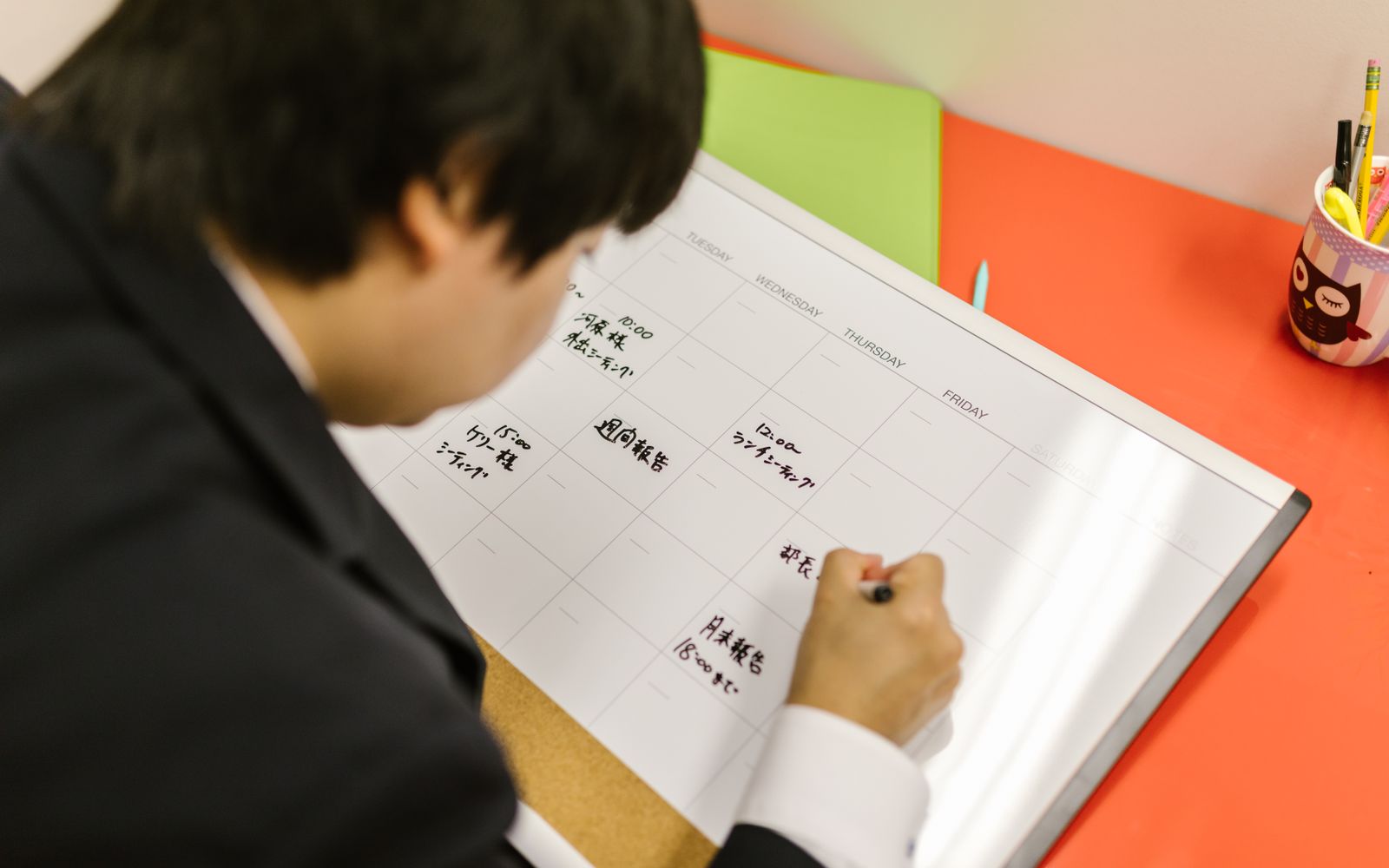 A manager writes the week's commitments onto a desk planner, Tuesday to Friday. Photo: RDNE Stock project / Pexels.